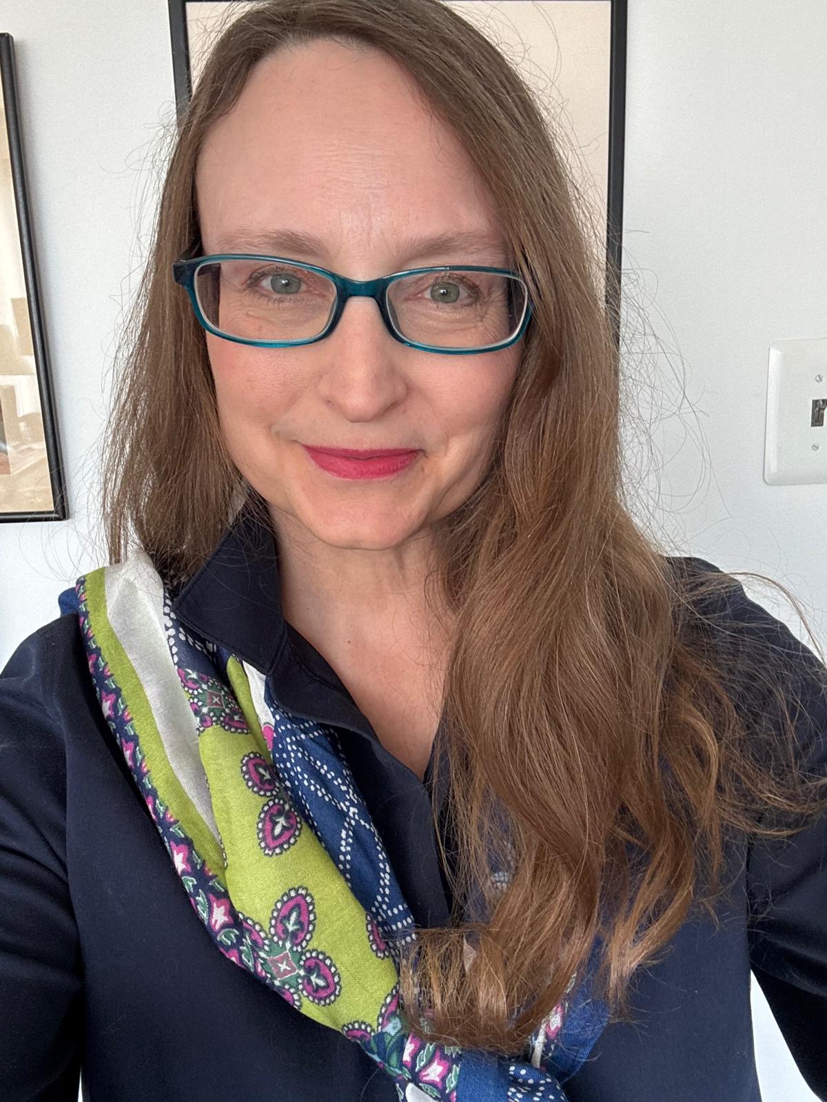 Michelle is a white woman with long brown hair and dark blue glasses