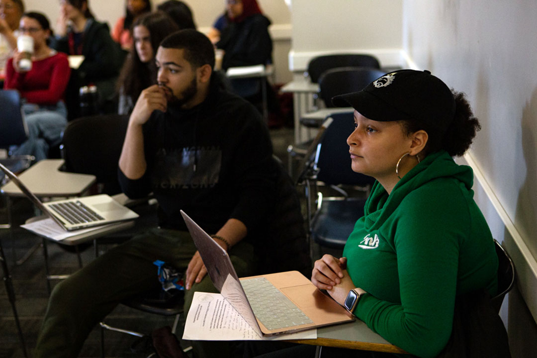 An HSSJ student in a baseball cap sits in the foreground of a class