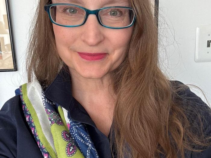 Michelle is a white woman with long brown hair and dark blue glasses